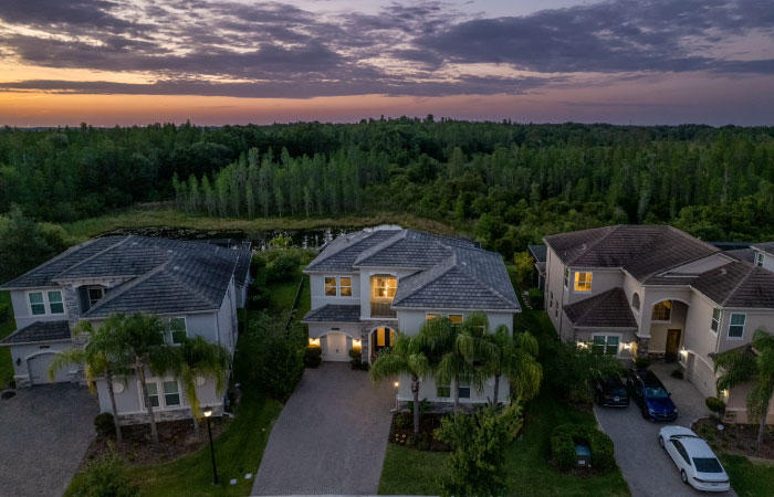 Aerial sunset view of three large single-family homes in Wesley Chapel, Florida — one of the many Tampa suburbs