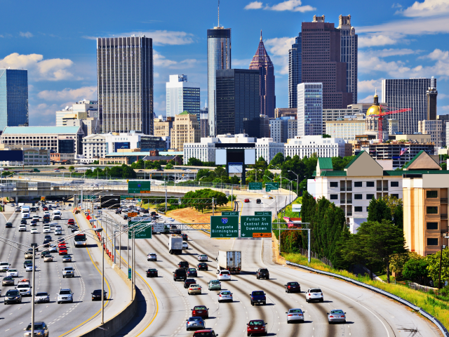 Several lanes of traffic moving in and out of the city of Atlanta, Georgia, on a sunny day.