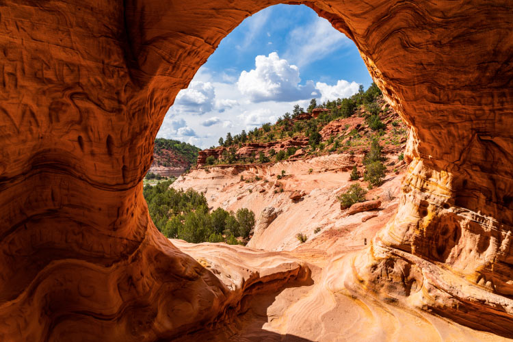 The view looking out from Moqui Cave near Kanab, Utah. This unique formation is made of red rocks, and the view is of a stunning natural Utah landscape.