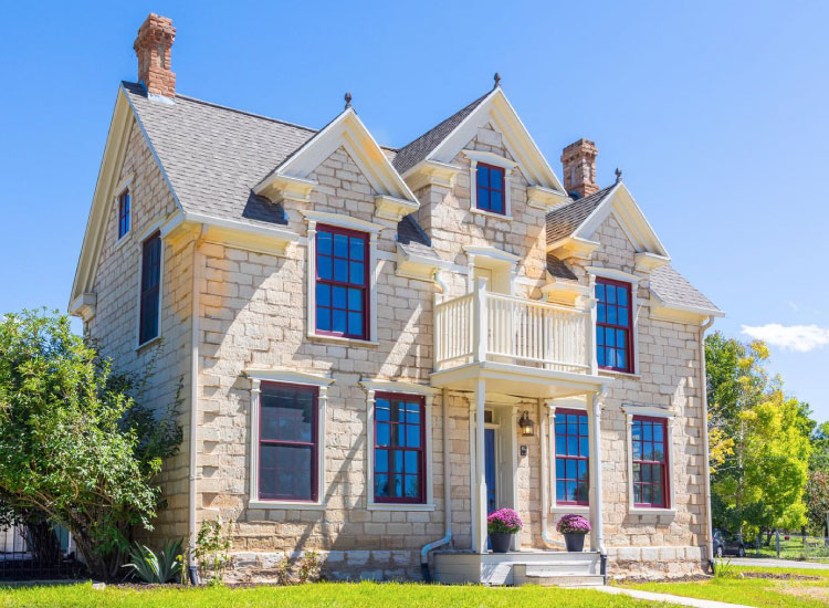 A historic two-story stone farmhouse in Spring City, Utah, dating back to 1879. The farmhouse is made of beautifully preserved white stones and features two chimneys.