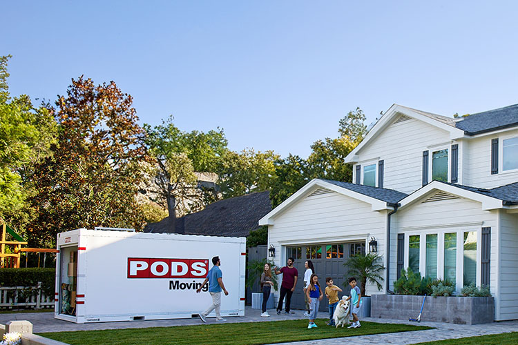 A family enlists help from friends to help load their PODS container in their home’s driveway