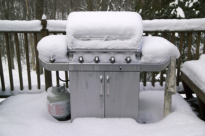 A patio grill covered in snow