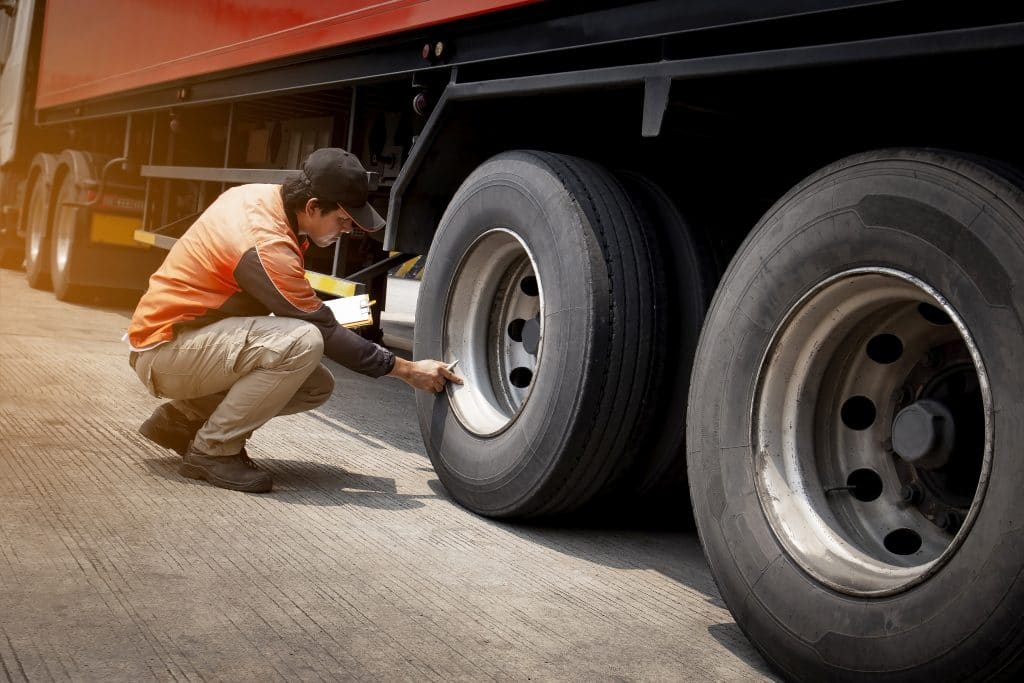 A trucker checking the tires on a semi truck