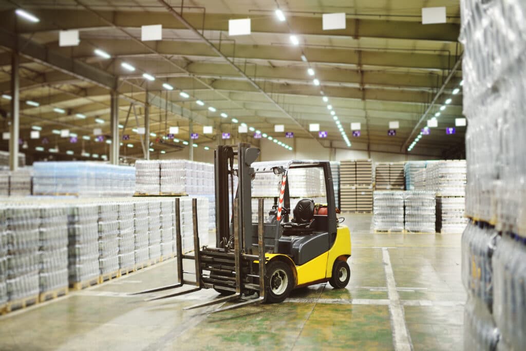 Yellow loader on the background of a huge industrial food warehouse with wholesale inventory 
